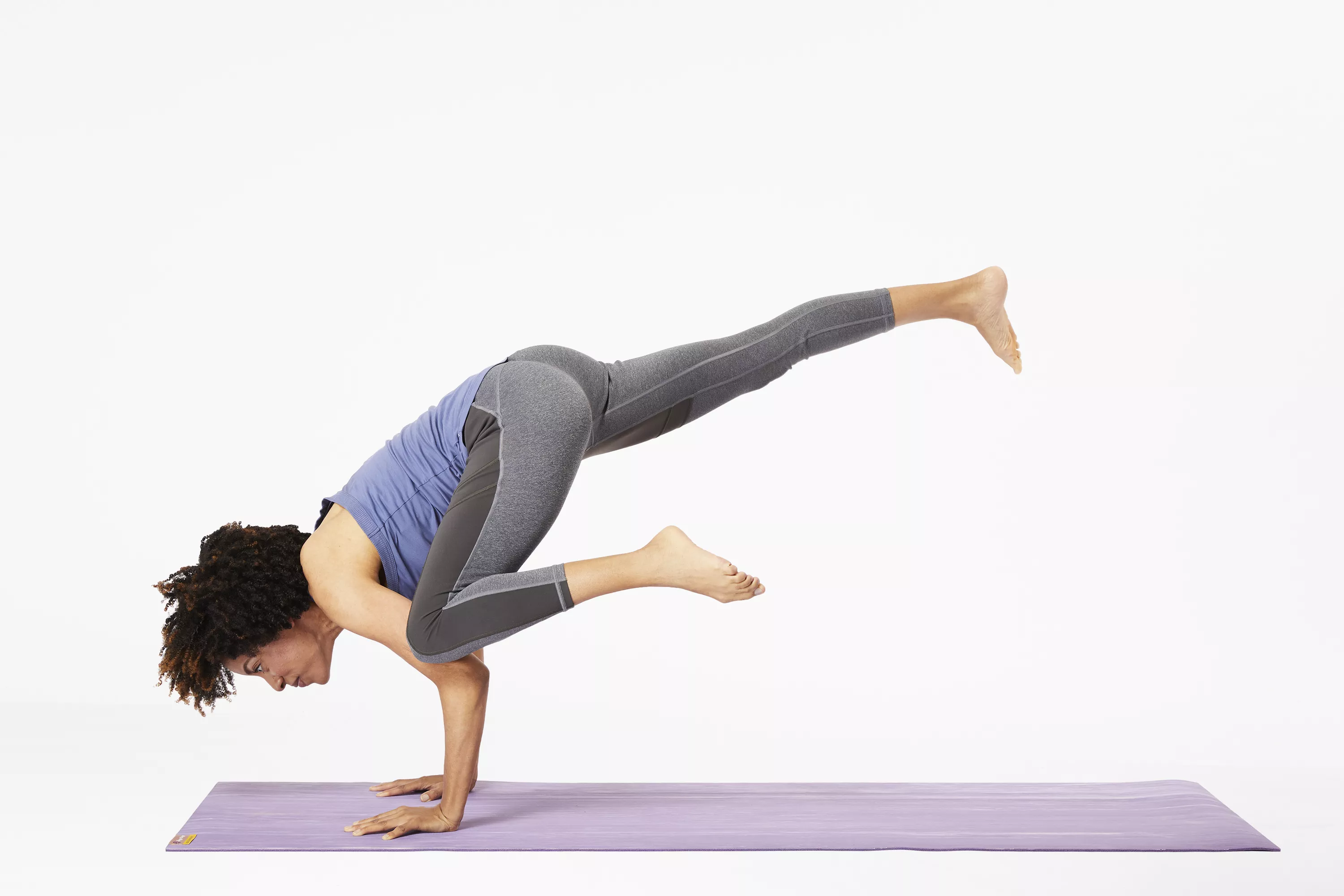 Woman on yoga mat doing flying crow pose