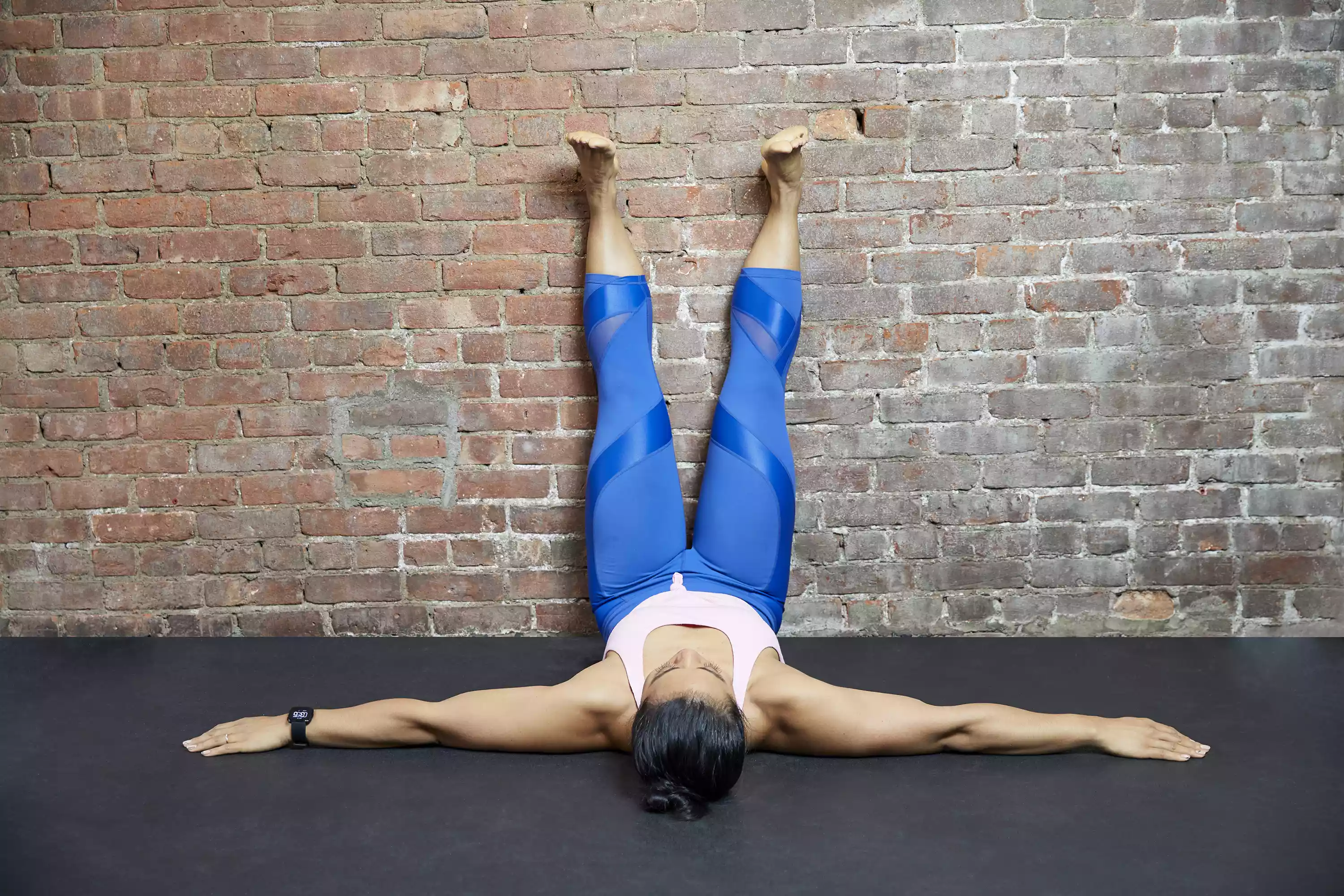 Woman with legs up a brick wall in gym