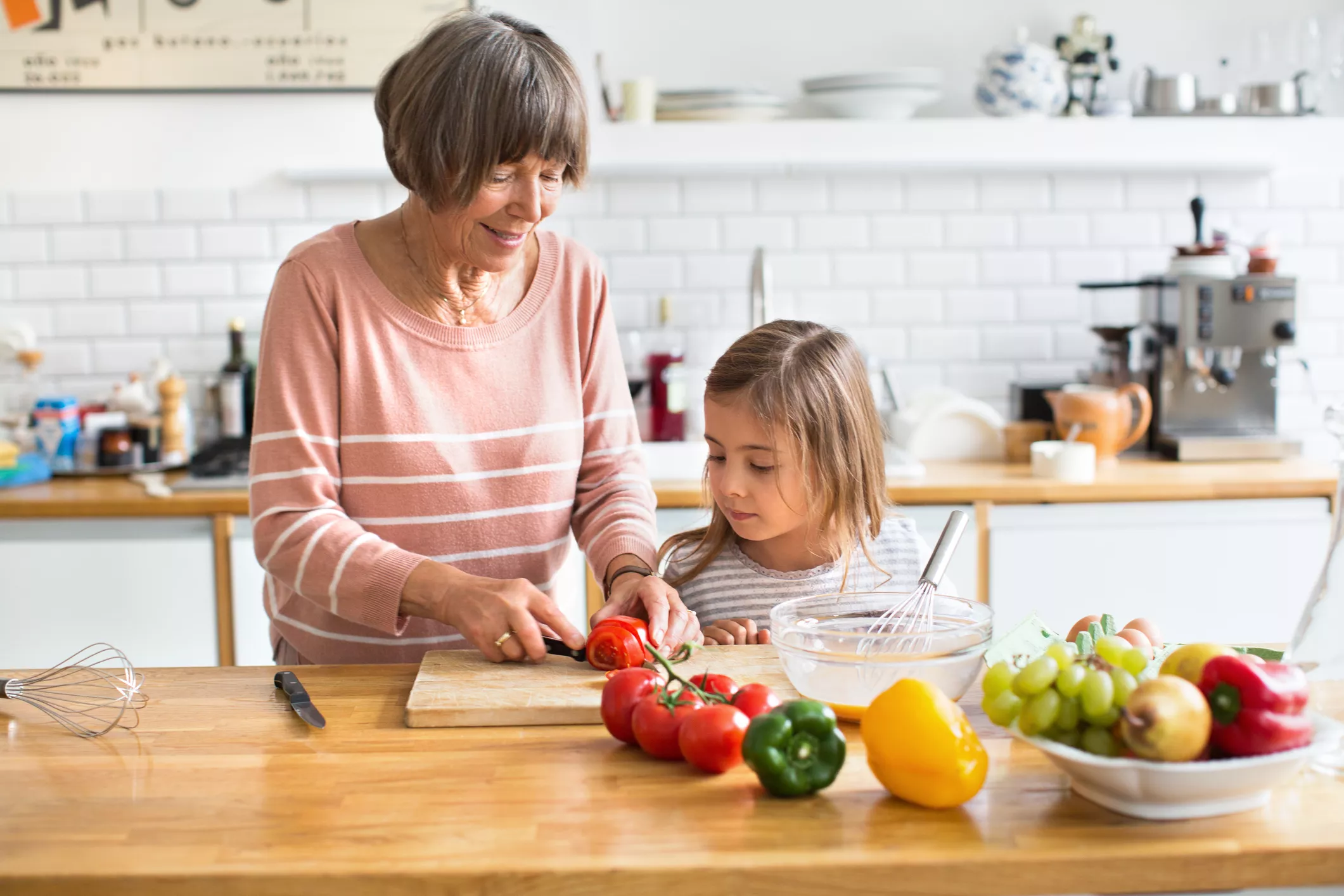Senior woman with her granddaughter chopping vegetables in kitchen