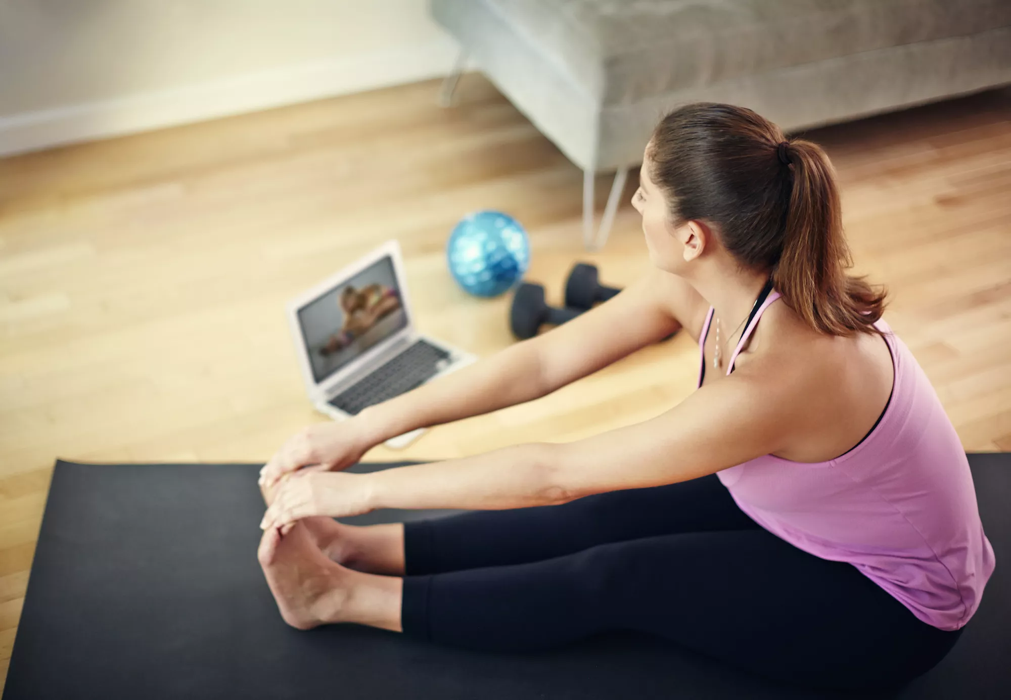 Woman doing stretches in front of laptop